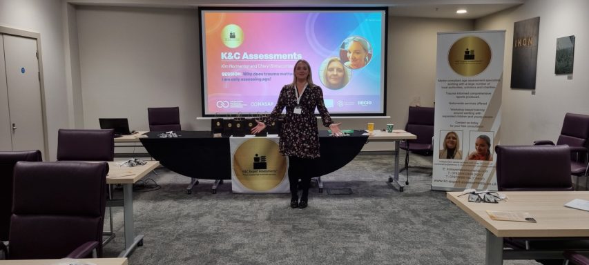 Special guests at the National Association of Supported Accommodation Conference Woman in a brown dress standing in an event space with a presentation backdrop.