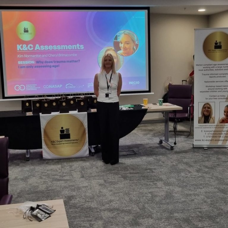 National Association of Supported Accommodation Conference 2024 Kim Normanton stands in front of a presentation screen and promotional banners in a meeting room.
